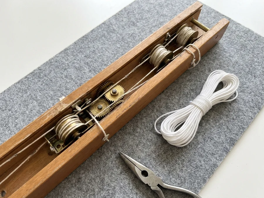 Close-up of a timber venetian headrail, cords and tilt mechanism being serviced