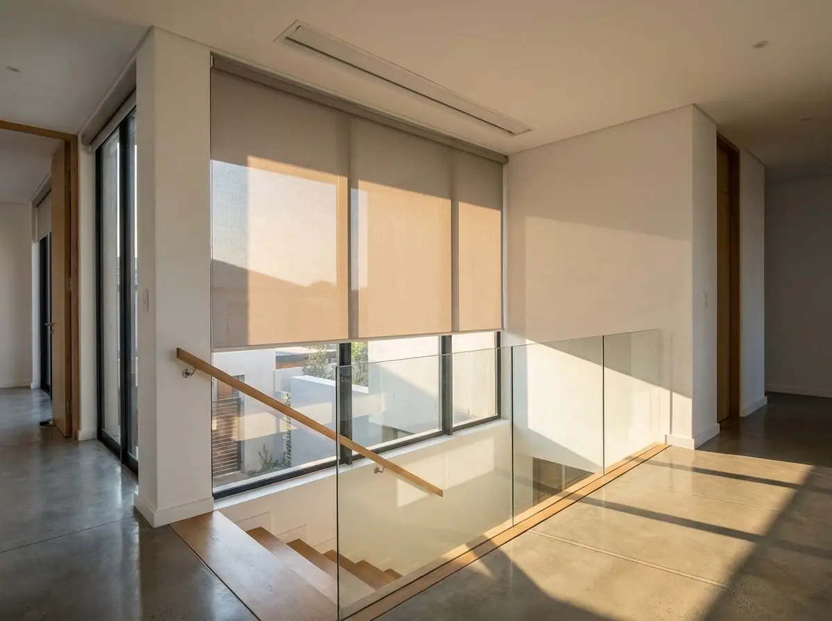 Motorised roller blind lowered over a double-volume stairwell window in a Sixfountains home